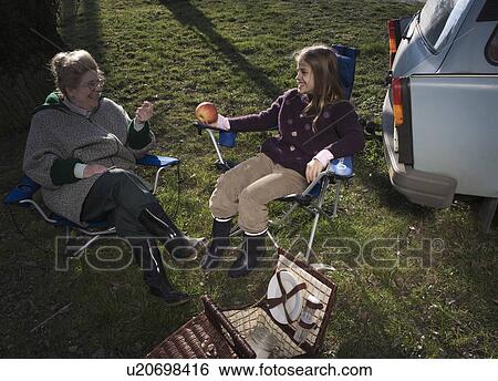 Grandmother and granddaughter (10-12) having picnic by car, smiling View Large Photo Image Stock Photograph - Grandmother and granddaughter (10-12) having picnic by car, smiling. Fotosearch