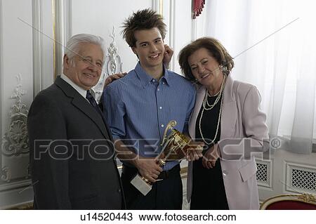 Grandparents presenting trophy to teenage boy (15-17) at family gathering View Large Photo Image Stock Image - Grandparents presenting trophy to teenage boy (15-17) at family gathering. Fotosearch