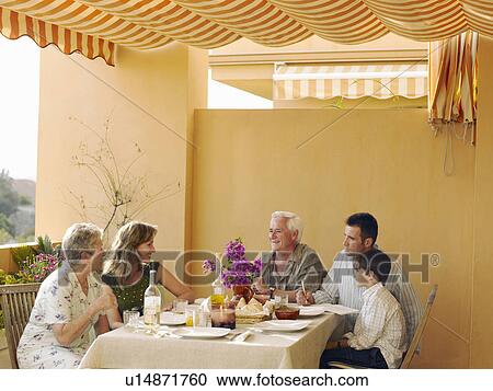 Multi-generational family sitting at dining table on balcony, talking View Large Photo Image Stock Image - Multi-generational family sitting at dining table on balcony, talking. Fotosearch