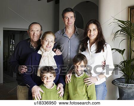 Stock Image - Multi-generational family standing in villa, smiling, portrait. Fotosearch