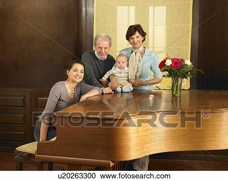 Stock Image - Multigenerational family (grandparents, mother and baby son (7months) by grand piano, portrait. Alicante, Spain.. Fotosearch