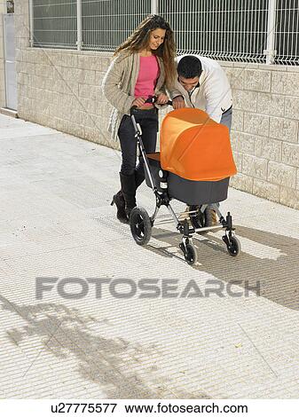 Stock Photo - Couple looking into pram on pavement, Alicante, Spain,. Fotosearch
