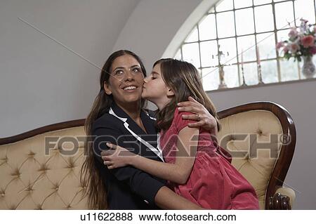 Daughter (9-11) kissing mother on sofa View Large Photo Image Stock Photo - Daughter (9-11) kissing mother on sofa. Fotosearch