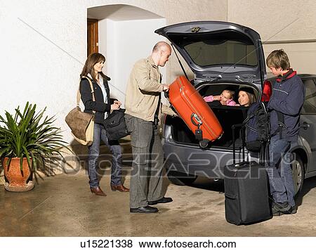 Stock Photo - Family loading luggage into car on driveway. Fotosearch