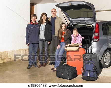 Stock Photo - Family standing by car and luggage, portrait. Fotosearch