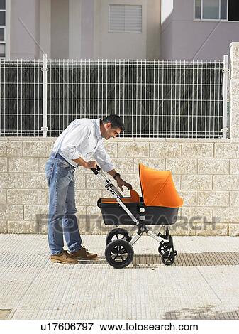 Father looking into pram on pavement, Alicante, Spain, View Large Photo Image Stock Photo - Father looking into pram on pavement, Alicante, Spain,. Fotosearch