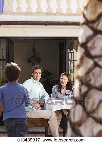 Parents sitting in garden smiling at son (4-6) View Large Photo Image Stock Photo - Parents sitting in garden smiling at son (4-6). Fotosearch