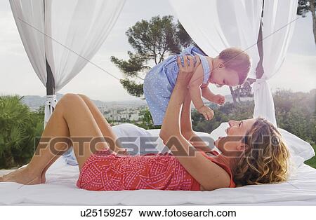 Stock Photo - Woman and baby on bed outdoors.. Fotosearch