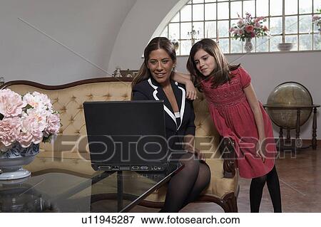 Stock Photo - Woman and daughter (9-11) looking at laptop. Fotosearch