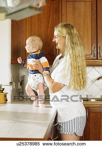 Woman holding baby up on kitchen counter smiling. View Large Photo Image Stock Photography - Woman holding baby up on kitchen counter smiling.. Fotosearch