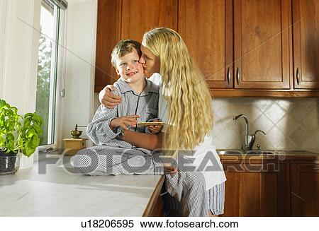 Woman kissing young boy holding sandwich in kitchen. View Large Photo Image Stock Photography - Woman kissing young boy holding sandwich in kitchen.. Fotosearch
