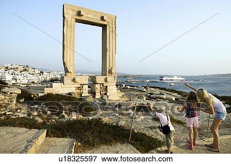 Stock Photo - Woman with young boy and young girl pointing at the Portara in Greece with tourists in background.. Fotosearch