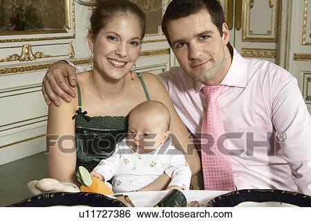 Stock Photograph - Young couple with baby (3-6 months) smiling, portrait. Fotosearch