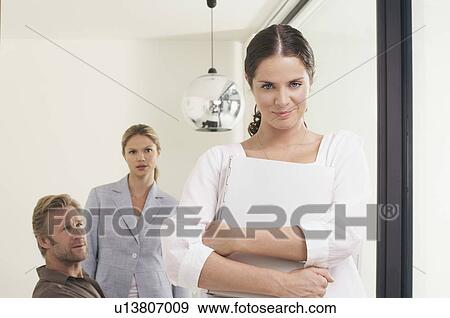 Stock Photo - Man and two women in office woman in foreground with file.. Fotosearch