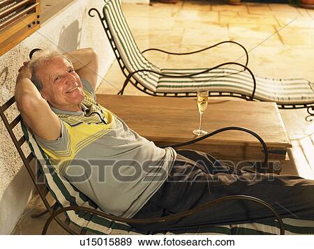 Senior man lying on sun lounger on terrace, smiling, portrait View Large Photo Image Stock Photo - Senior man lying on sun lounger on terrace, smiling, portrait. Fotosearch