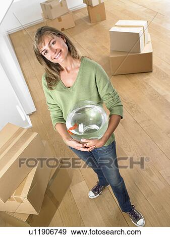 Woman holding fishbowl in new home smiling. View Large Photo Image Stock Photo - Woman holding fishbowl in new home smiling.. Fotosearch