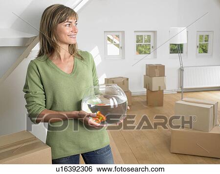 Woman holding fishbowl in new home smiling. View Large Photo Image Stock Photograph - Woman holding fishbowl in new home smiling.. Fotosearch