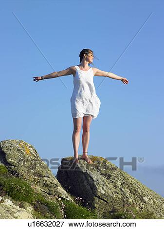 Woman standing on cliff holding out her arms out. View Large Photo Image Stock Photo - Woman standing on cliff holding out her arms out.. Fotosearch