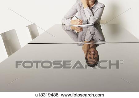 Stock Photograph - Young business woman at desk with reflections.. Fotosearch