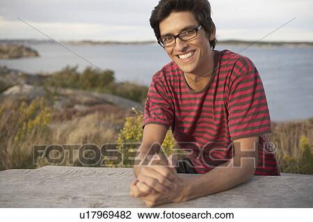 Stock Image - Young Man outdoors sitting at table.. Fotosearch