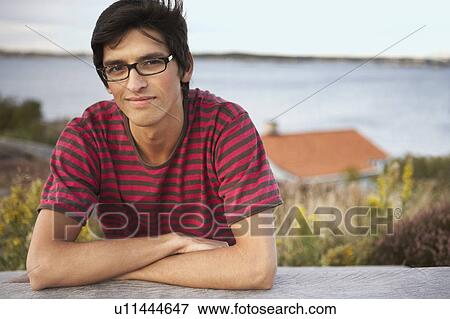 Stock Photo - Young Man outdoors sitting at table.. Fotosearch