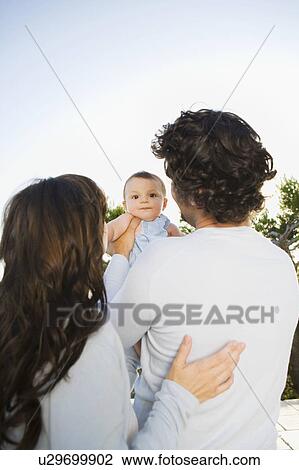 Couple holding a baby outdoors. View Large Photo Image Stock Image - Couple holding a baby outdoors.. Fotosearch