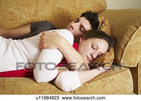 Stock Image - Embracing couple lying on sofa. Fotosearch