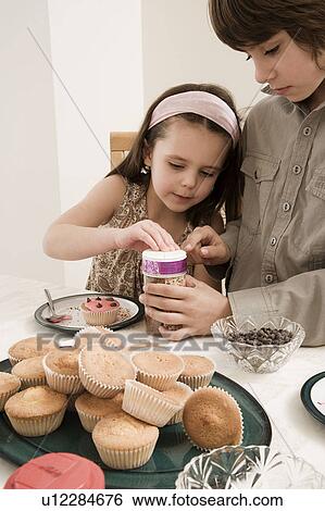 Girl and boy decorating cakes View Large Photo Image Stock Photograph - Girl and boy decorating cakes. Fotosearch