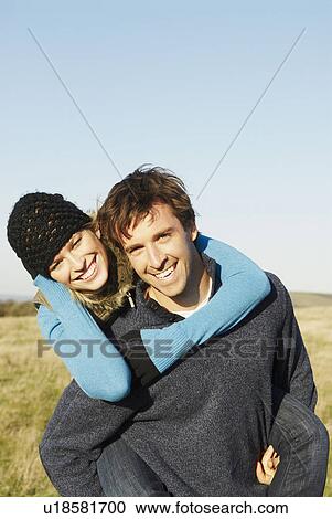 Stock Image - Man giving woman a piggyback. Fotosearch