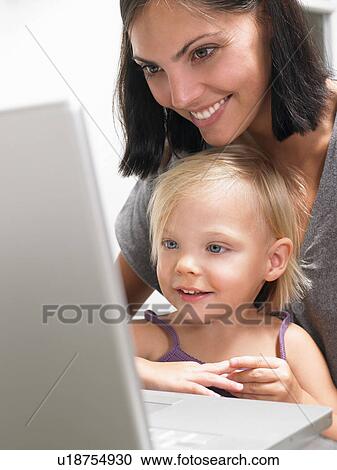 Mother and daughter looking at a laptop View Large Photo Image Stock Image - Mother and daughter looking at a laptop. Fotosearch