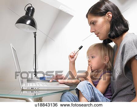 Mother and daughter looking at a laptop View Large Photo Image Stock Photograph - Mother and daughter looking at a laptop. Fotosearch