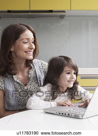 Stock Image - Mother and young girl using laptop. Fotosearch