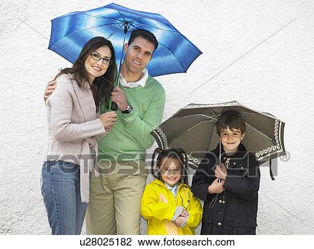 Parents, boy (6-8) and girl (4-6) holding umbrellas, smiling View Large Photo Image Stock Image - Parents, boy (6-8) and girl (4-6) holding umbrellas, smiling. Fotosearch