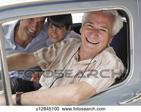 Stock Image - Boy (8-10) sitting in car with father and grandfather, portrait. Fotosearch