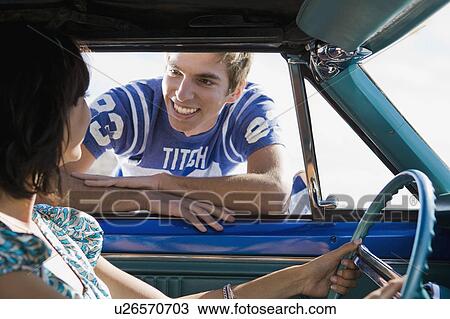 Man leaning into car smiling at woman. View Large Photo Image Stock Image - Man leaning into car smiling at woman.. Fotosearch