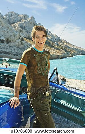 Stock Photo - Man standing by car smiling.. Fotosearch