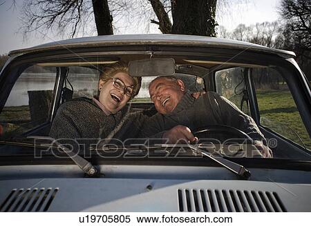 Stock Photography - Senior couple sitting in car, laughing, view through window. Fotosearch
