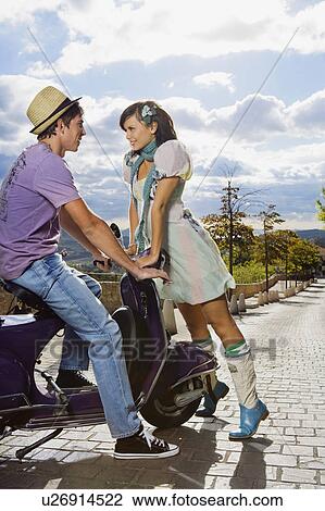 Stock Image - Woman flirting with man on scooter.. Fotosearch