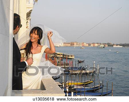 Stock Photo - Bride and groom on balcony having a toast. Venice, Italy.. Fotosearch