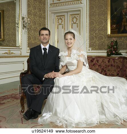 Stock Photo - Bride and groom sitting smiling, portrait. Fotosearch