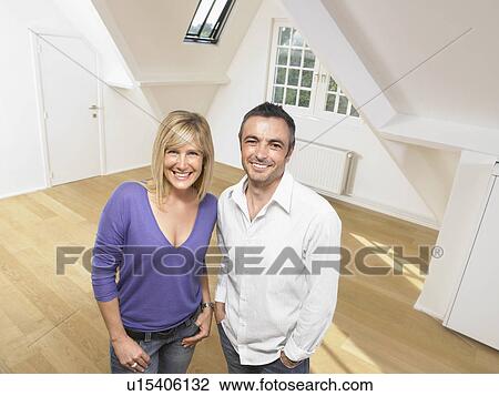 Stock Image - Couple standing in empty loft.. Fotosearch