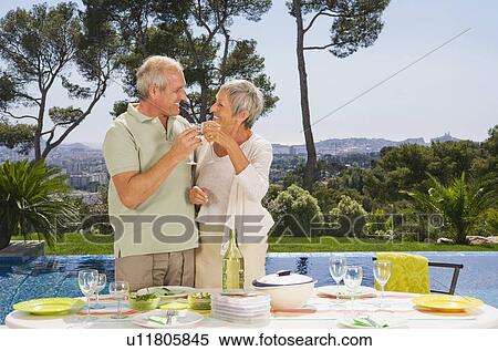 Stock Photography - Man and woman drinking by poolside.. Fotosearch