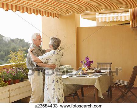 Senior couple dancing beside dining table on balcony View Large Photo Image Stock Image - Senior couple dancing beside dining table on balcony. Fotosearch