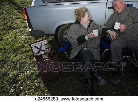 Senior couple having picnic by car, holding cups, smiling View Large Photo Image Stock Image - Senior couple having picnic by car, holding cups, smiling. Fotosearch