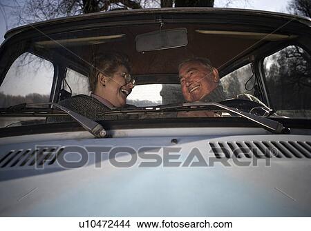 Picture - Senior couple sitting in car, smiling at each other. Fotosearch