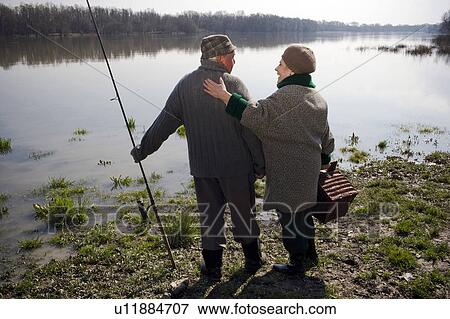 Senior couple standing by river, holding fishing rod and basket View Large Photo Image Stock Photo - Senior couple standing by river, holding fishing rod and basket. Fotosearch