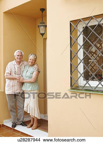 Picture - Senior couple standing on front porch, smiling, portrait. Fotosearch