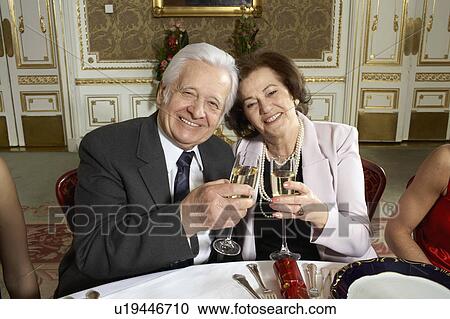 Stock Image - Senior couple toasting with glasses, smiling, portrait. Fotosearch