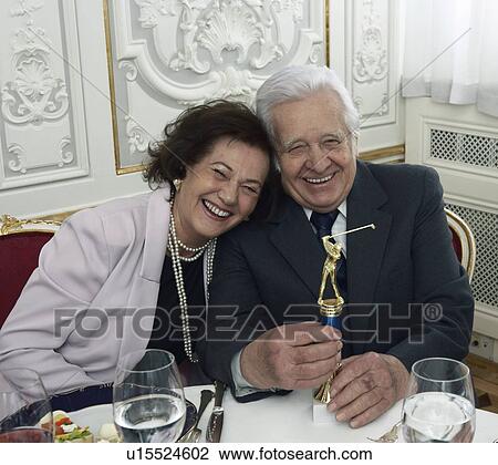 Stock Image - Senior couple with golf trophy, smiling, portrait. Fotosearch
