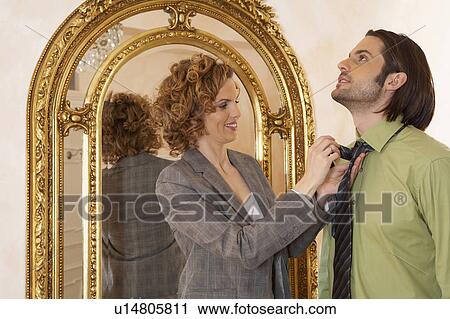 Stock Image - woman adjusting young man's tie. Fotosearch